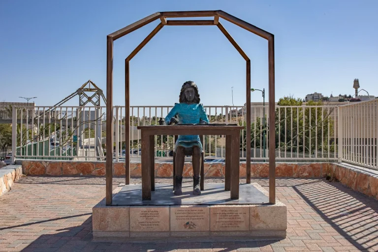אנדרטת אנה פרנק של סם פיליפ במעלה אדומים, אנה יושבת ליד שולחן בתוך מסגרת המדמה את חלל המסתור