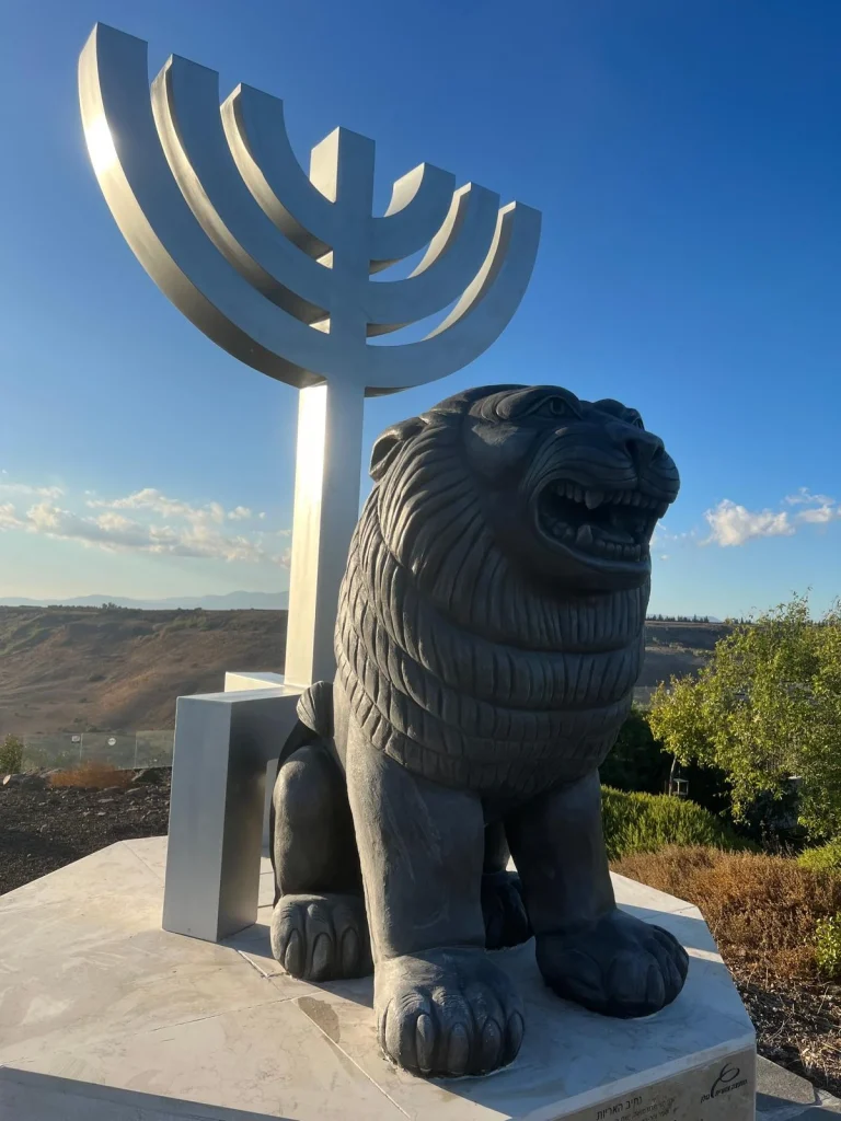 תקריב האריה בעל הפה הפתוח והמנורה שמאחוריו בעין קשתות