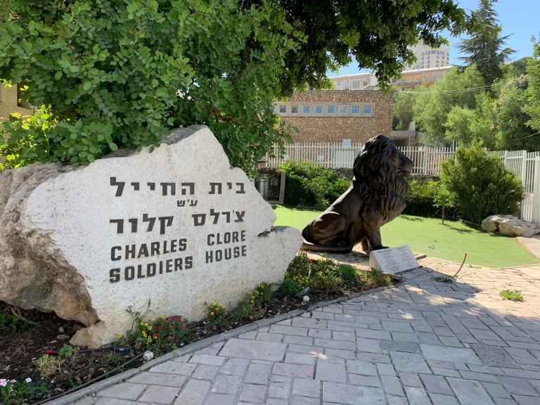 אריה יהודה של סם פיליפ יושב לצד אבן הכניסה לבית החייל ע״ש צ׳רלס קלור בירושלים
