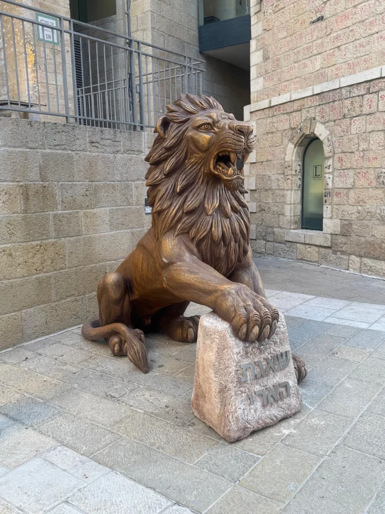 מבט צד על אריה ממילא של סם פיליפ כשכפתו נשענת על אבן כתובה