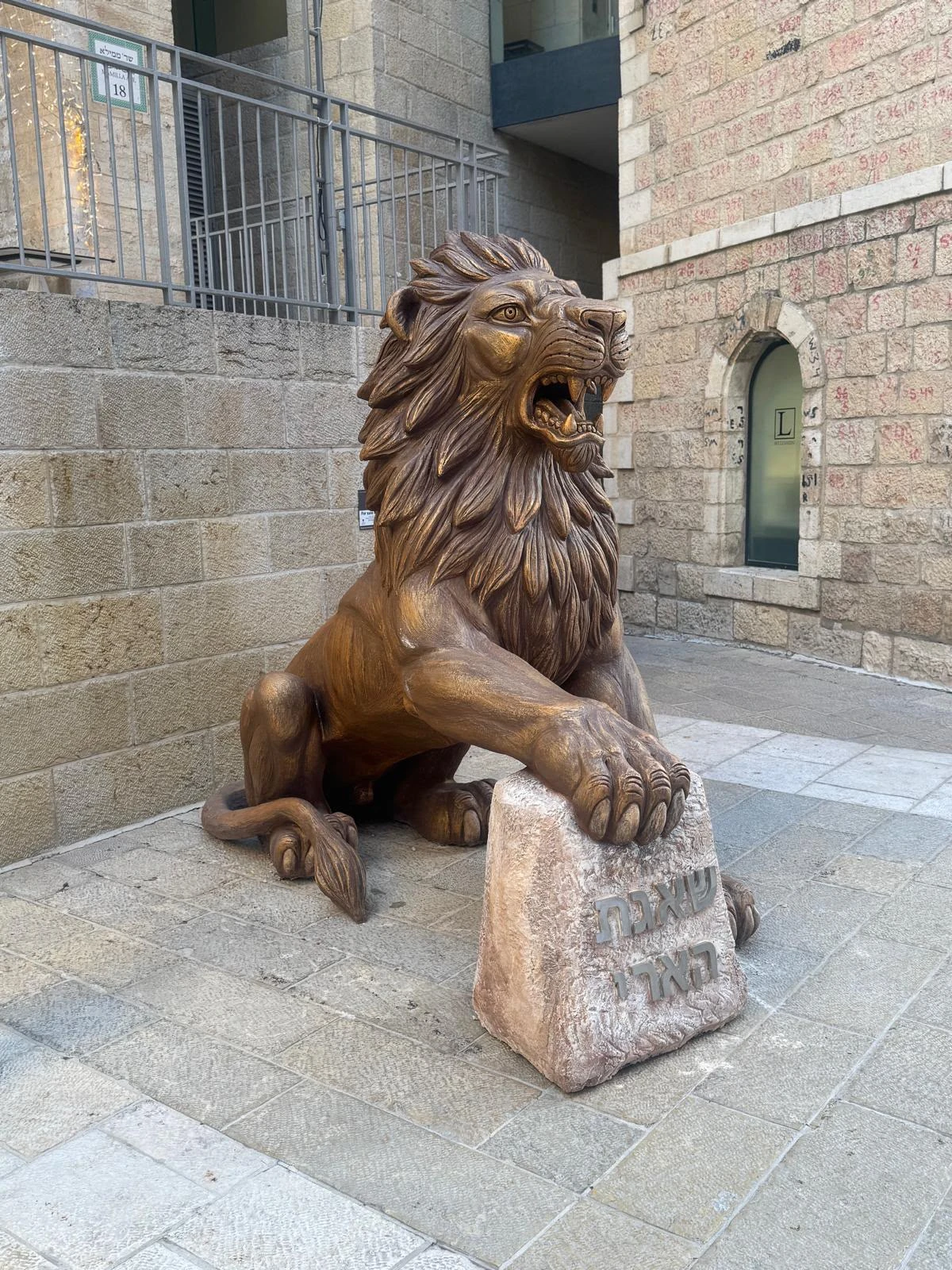 מבט צד על אריה ממילא של סם פיליפ כשכפתו נשענת על אבן כתובה