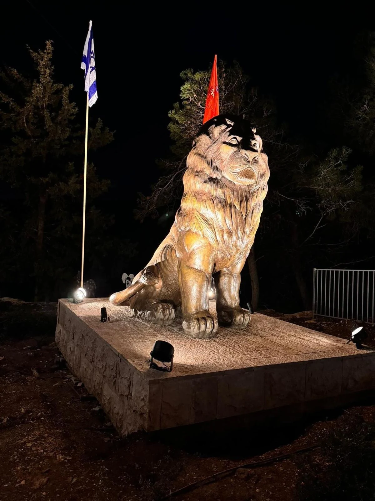 אריה נשר של סם פיליפ מואר בלילה על בסיס אבן בכניסה לפארק נשר