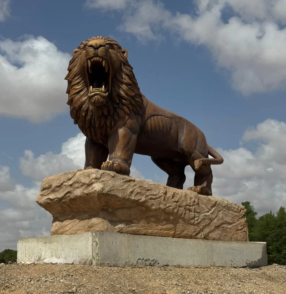 אריה אופקים של סם פיליפ עומד ושואג על בסיס אבן גבוה
