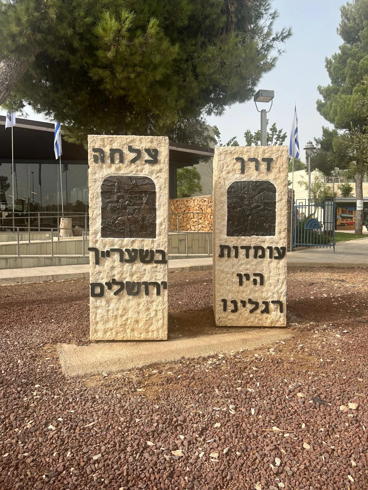 שתי אבנים ירושלמיות זו לצד זו עם המילים ״דרך צלחה״, תבליטי ברונזה ושורות מהפסוק ״עומדות היו רגלינו בשעריך ירושלים״